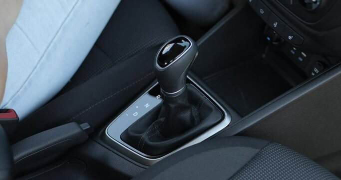 Female hand shifts gears. Automatic transmission, automatic gear shift, is moved from P (Park) to D (Drive) and R position. Top view.