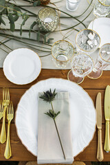 Decorated plate with fork and spoon. Table set up in boho style with pampas grass and greenery