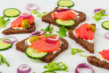 Appetizer, open sandwich with salmon, onion and cucumber on white background. Traditional Italian or Scandinavian cuisine. Concept of proper nutrition and healthy eating. Close up