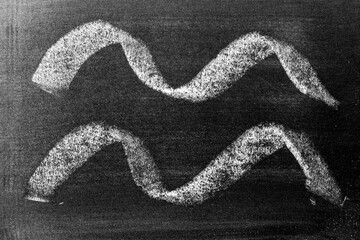 White color chalk hand drawing in set of curve or wavy line shape on black board background