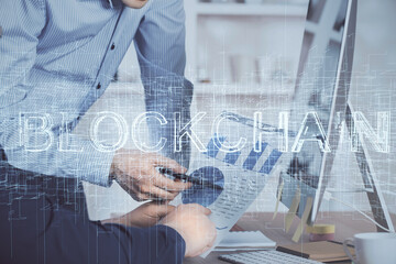 Crypto currency theme hologram with businessman working on computer on background. Concept of blockchain. Multi exposure.