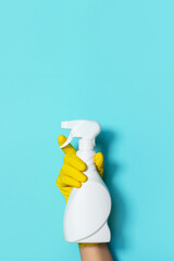 Hand in glove holding white plastic bottle of cleaning product, household chemicals. Copy space....