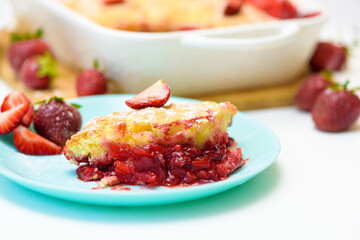 homemade strawberry cobbler made from ripe fresh strawberries. cut strawberry pie on a blue plate on a light background