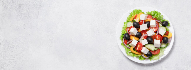 Greek salad with cheese and fresh vegetables on white background.