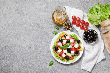 Greek salad with cheese and fresh vegetables on grey background.