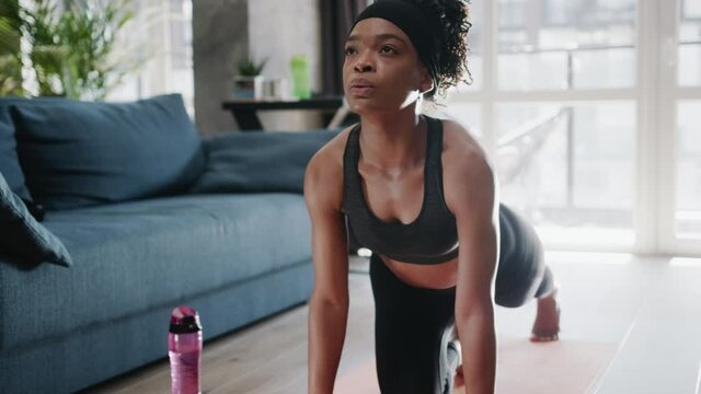 Sporty african american woman in sportswear doing workout training strength practicing effort domestic fitness aerobics sport fit at home slow motion