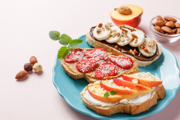 Sweet sandwiches with fruits and berries on pink colorful background.