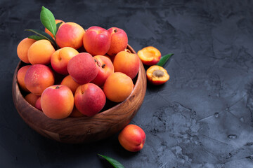 Ripe apricots on black background. Top view, copy space. Fruit banner. Healthy vegetarian food, detox or diet concept. Fruit summer concept. Bowl of harvested apricots for jam