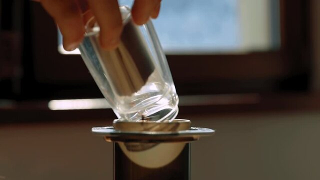 A man pours freshly ground coffee into an aeropress in slow-motion