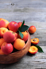 Ripe apricots with leaves on wooden background. Top view, copy space. Fruit banner. Healthy vegetarian food, detox or diet concept. Fruit summer concept. Bowl of harvested apricots for jam