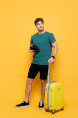 handsome man with suitcase and binoculars ready for summer vacation on yellow