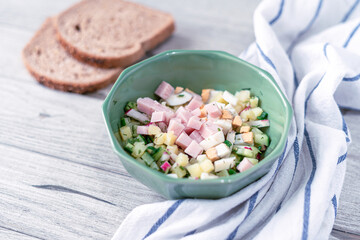 Traditional russian cold soup okroshka ingredients with some of its cooking components on a gray wooden background with bread. Salad with copy space