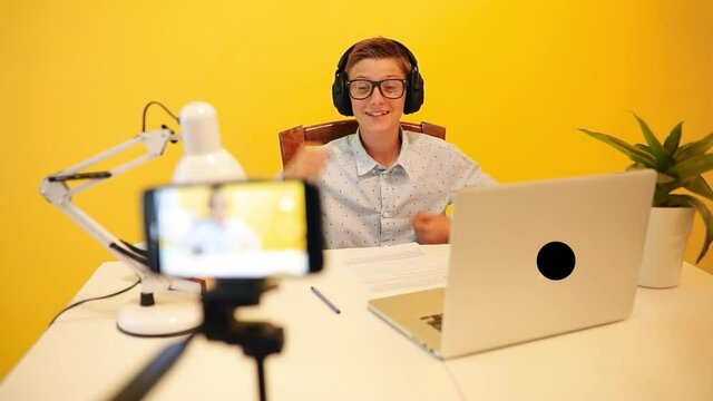 The outbreak of coronavirus and the closure of schools. Schoolboy teen guy watch online education lesson, happy to communicate with the teacher on the Internet on a laptop, sitting at a Desk, on an ye