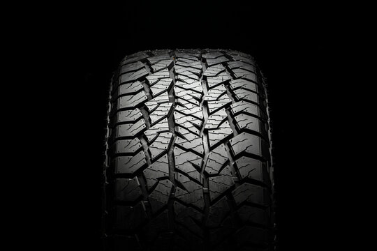 mud all-season all terrain tire with a powerful tread. Front view on a black background close up