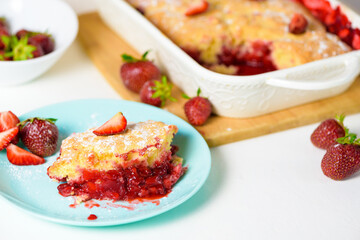 homemade strawberry cobbler made from ripe fresh strawberries. cut strawberry pie on a blue plate on a light background