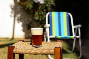 glass of craft beer on wooden table in the garden