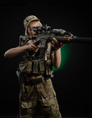Fototapeta premium a sexy girl in military airsoft overalls poses with a gun in her hands on a dark background