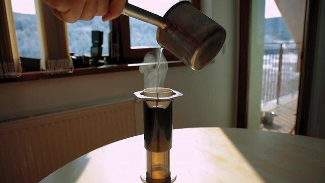 Hot water being poured into an aeropress in an apartment with a mountain view in the background