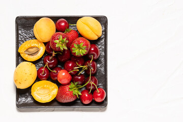 Assortment of fresh organic fruit on white concrete background top view. Healthy summer dessert on the table.
