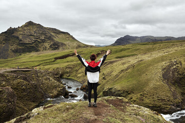 Pretty young girl exploring the exploring the green landscape around skogafos waterfall in Iceland.