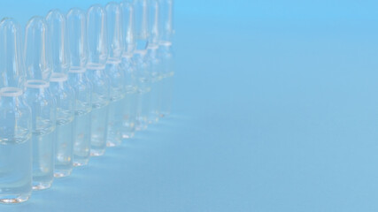 ten ampoules with colorless medicine on a blue background in a row