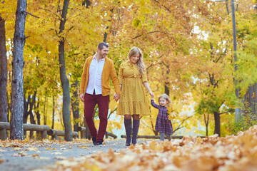 Family walking in the park in yellow autumn.