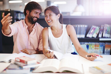 Young couple taking a self portrait in light interior,two beautiful teens posing for a selfie while sitting in light library preparing for exams, young students taking a photo of themselves in library