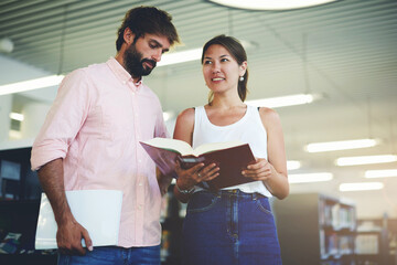 Portrait of young couple of students holding some books while preparing for university exams,...