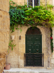Vertical photo of green aged entrance door classical colonial style. Birgu, Malta