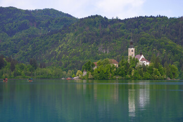 Fototapeta na wymiar Morning at Lake Bled and Julian Alps in the background. The lake island and charming little church dedicated to the Assumption of Mary are famous tourist attraction in Slovenia
