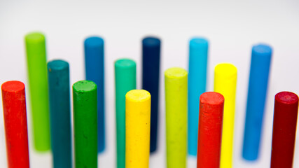 Crayons of different colours,  haphazardly displayed on a white background standing upright with use of selective focus and a slightly elevated view of the crayon's top.