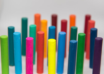 Top angle view of Crayons of different colours,  haphazardly displayed on a white background standing upright with use of selective focus.