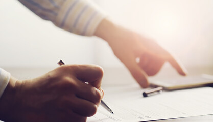 Business meeting. A man signs a contract. Male hand with pen makes notes in the office.