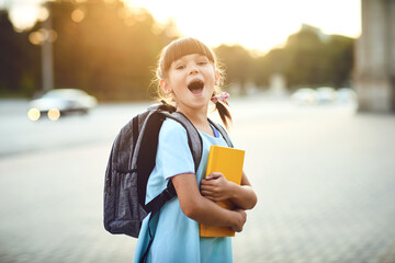 Happy little schoolgirl with a backpack on her way to school.