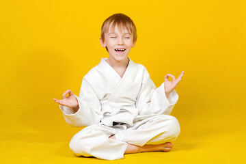 Little boy practicing yoga. Child in kimono practices and meditates. Spirit of martial arts.
