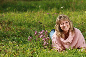Naklejka na ściany i meble Senior woman lying in the grass with flowers around her