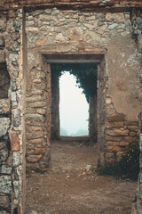 Sequence of doors of a demolished house that end in a foggy landscape.