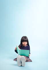 Little asian girl sitting on floor and reading book. Education and school concept.