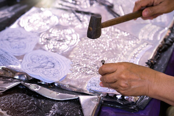 Silverware making. A craftsman carves intricate drawings into silver or aluminium which is used for...