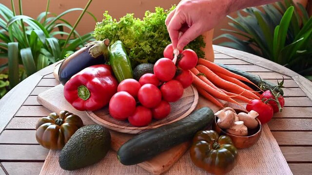 hand holding a string of tomatoes among freshly picked fresh vegetables