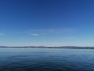 Beautiful calm day on the sea with clear blue sky and island with pine trees