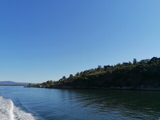 Obraz premium Beautiful calm day on the sea with clear blue sky and island with pine trees