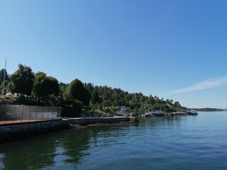 Beautiful calm day on the sea with clear blue sky and island with pine trees