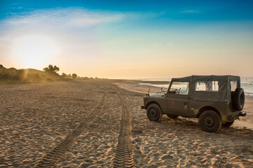 Vintage jeep parked on a deserted beach at sunrise in summer time , clear sky with no clouds , holiday scene © august.columbo