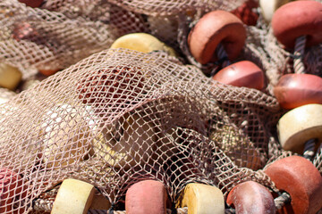 Old green and grey fishernet and other fishermens equipment, yellow and orange lifting bowls