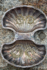 Brass metal spiral earrings on decorative silver shell background