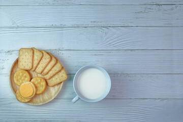 Cookies on a wooden plate with a glass of fresh milk arranged beautifully and served as breakfast.