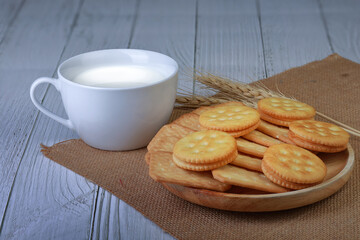 Cookies on a wooden plate with a glass of fresh milk arranged beautifully and served as breakfast.