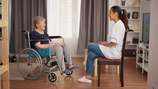 Senior woman in wheelchair having a conversation with nurse. Old person retirement home, healthcare nursing, health support, social assistance, doctor and home service