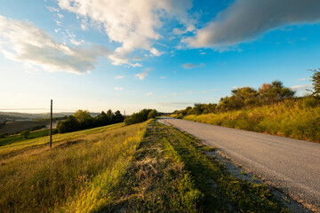 Country road at sunset, blue sky with clouds